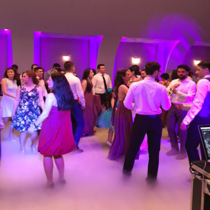 Invitati dansand inconjurati de lumini arhitecturale mov si fum usor