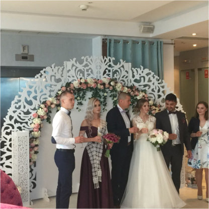 Miri si invitati facand poze avand pe fundal panou floral