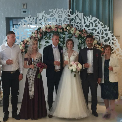 Miri si invitati pozand in fata unui panou floral